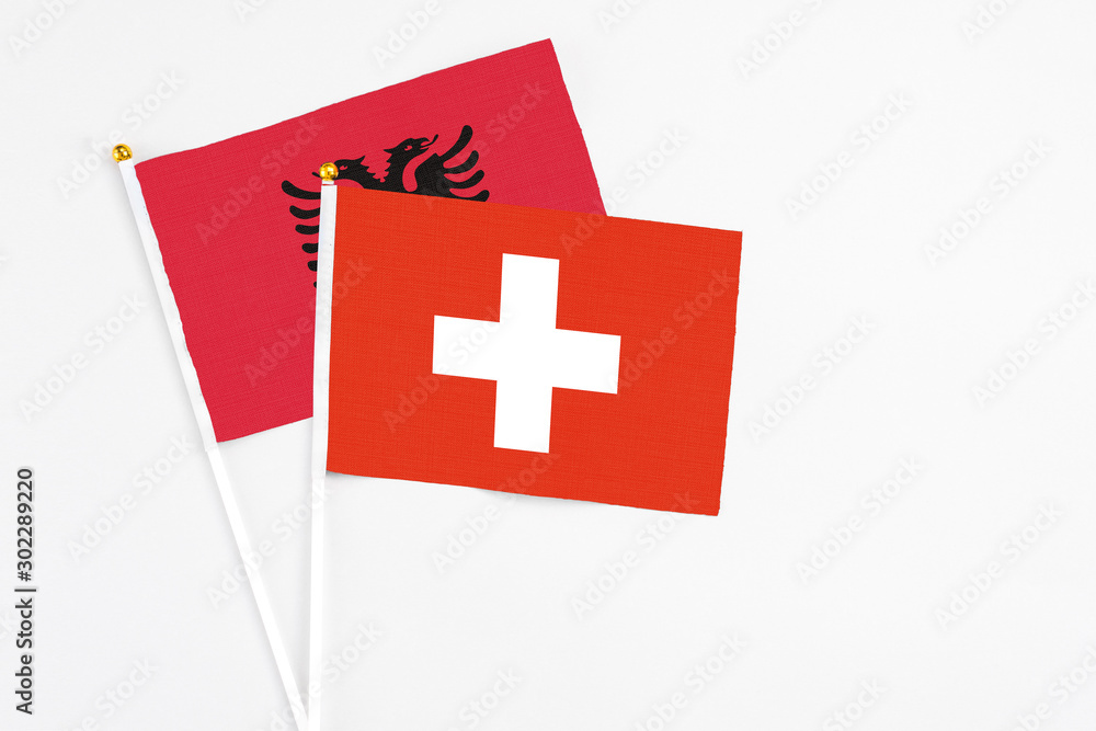 Switzerland and Albania stick flags on white background. High quality fabric, miniature national flag. Peaceful global concept.White floor for copy space.