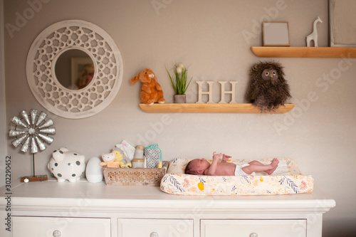 Newborn baby girl laying on changing table in diaper at home