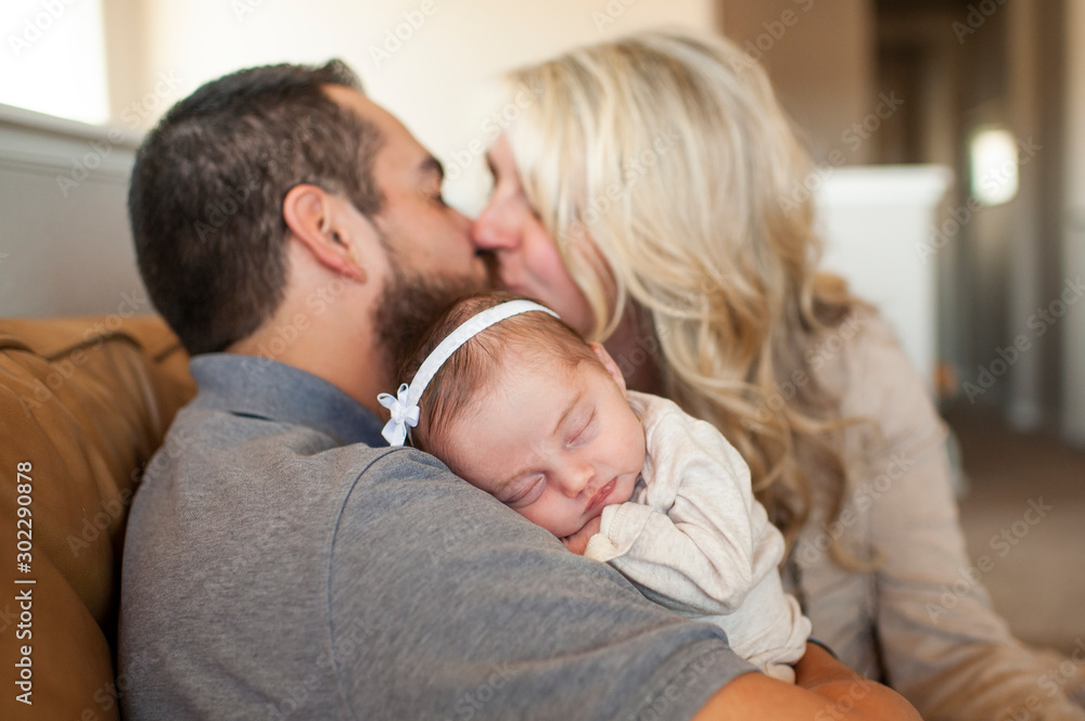 Close up of newborn baby sleeping with parents kissing in background Close up of newborn baby sleeping with parents kissing in background