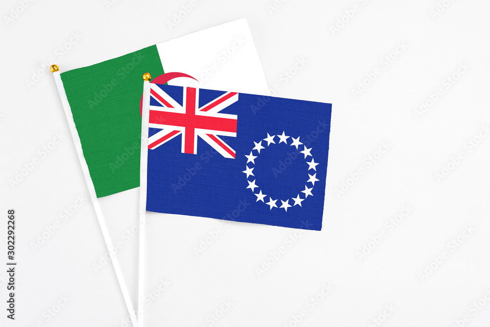 Fototapeta premium Cook Islands and Algeria stick flags on white background. High quality fabric, miniature national flag. Peaceful global concept.White floor for copy space.
