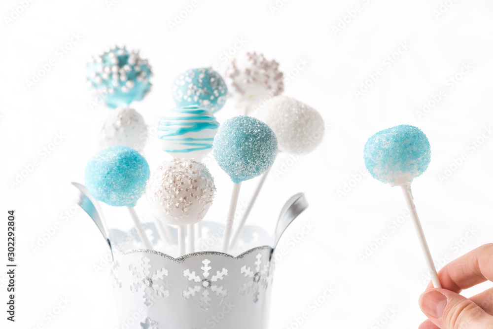 Decorated blue and white cake pops with hand holding.