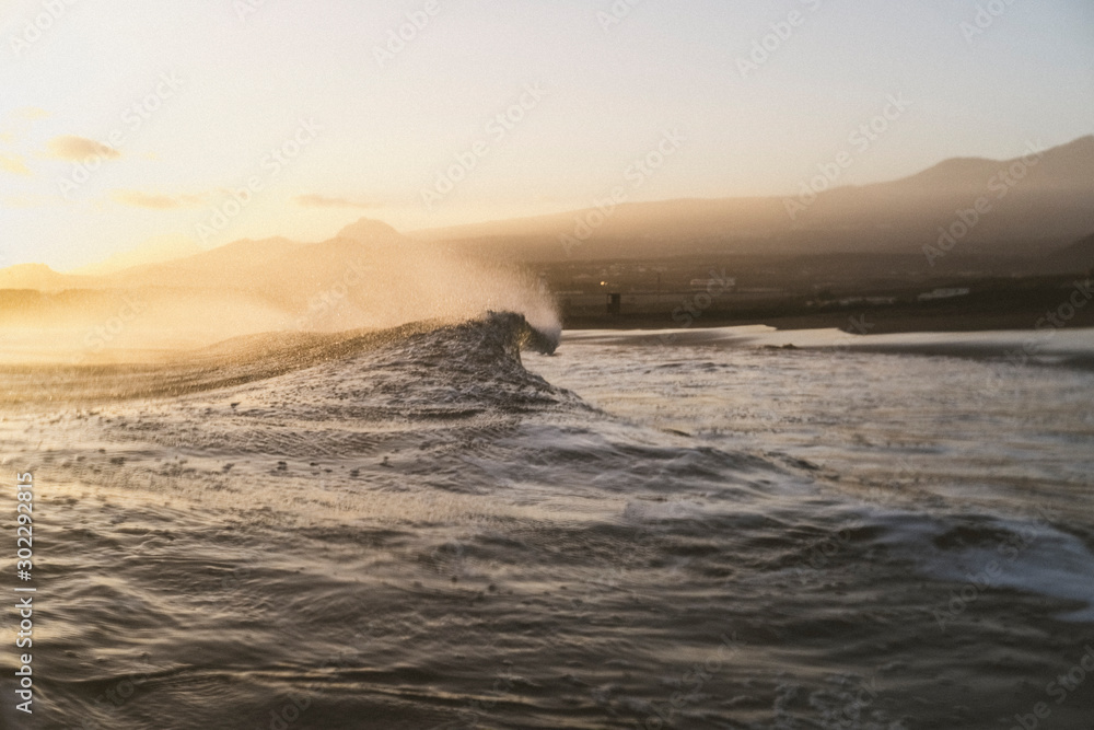 Moody beach scene of a wave breaking with shoreline in background Moody beach scene of a wave breaking with shoreline in background