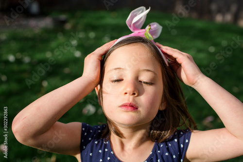 A beautiful little girl with serious expression wears flower for a hat