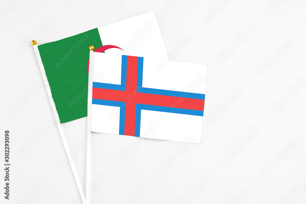 Faroe Islands and Algeria stick flags on white background. High quality fabric, miniature national flag. Peaceful global concept.White floor for copy space.