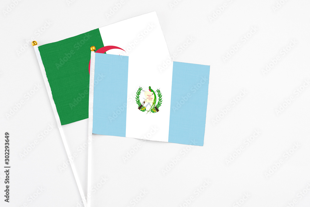 Guatemala and Algeria stick flags on white background. High quality fabric, miniature national flag. Peaceful global concept.White floor for copy space. Guatemala and Algeria stick flags on white background. High quality fabric, miniature national flag. Peaceful global concept.White floor for copy space.