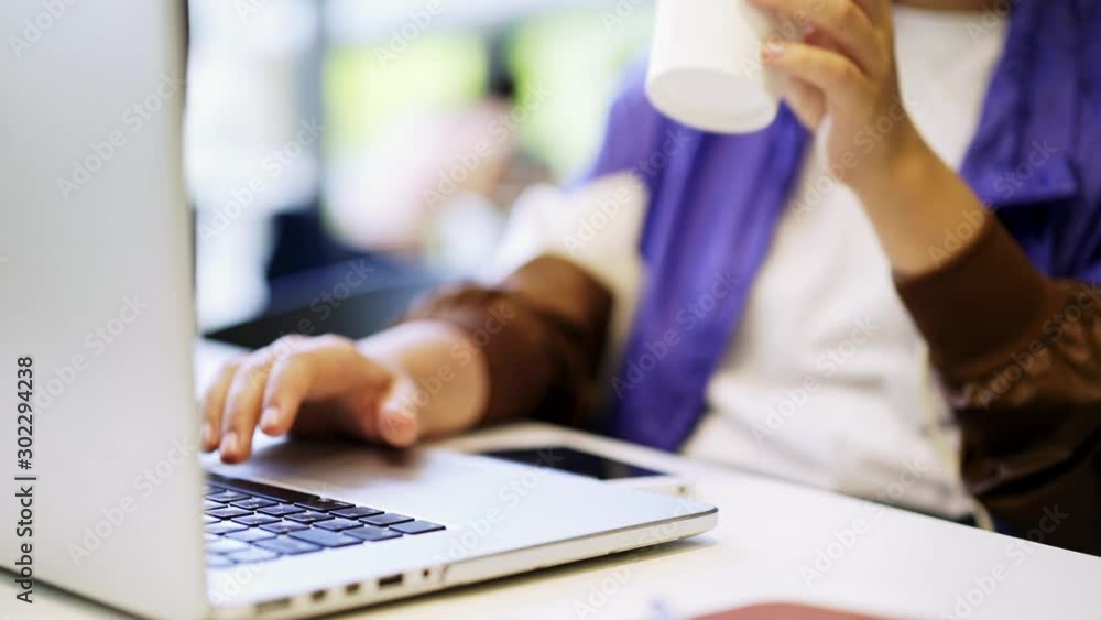 Young woman working on laptop online via free wifi in public place. Detail shot female hands typing on keyboard at the table in cafeteria, student prepare to exam on notebook, designer work distance Young woman working on laptop online via free wifi in public place. Detail shot female hands typing on keyboard at the table in cafeteria, student prepare to exam on notebook, designer work distance