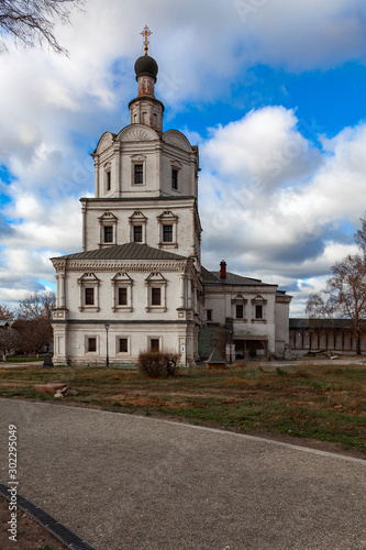 An ancient Orthodox church on the territory of the Andrei Rublev Museum in Moscow against a cloudy sky. In the foreground is a gravel path