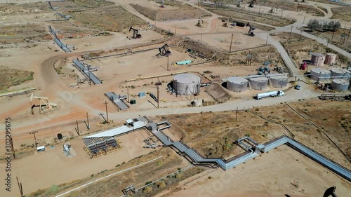 Aerial view of Oil Pumpjack and highway road. Oil industry equipment. Morning, blue sky. Camera move forward. California. USA country