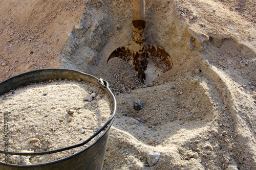 Loading sand with a shovel into a bucket