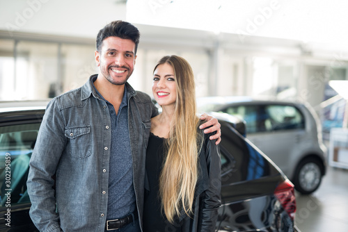 Happy couple in front of their new car in a showroom © Minerva Studio