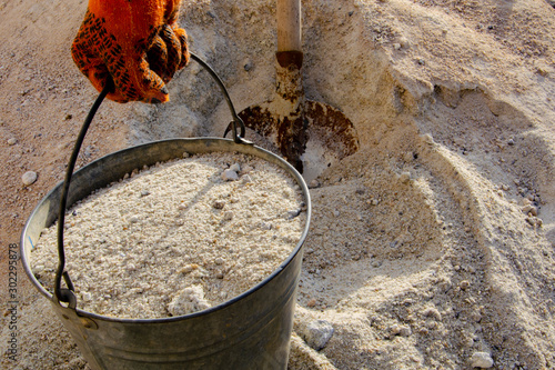 Loading sand with a shovel into a bucket
