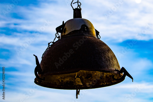 Old, rusty lantern hanging on a sky background