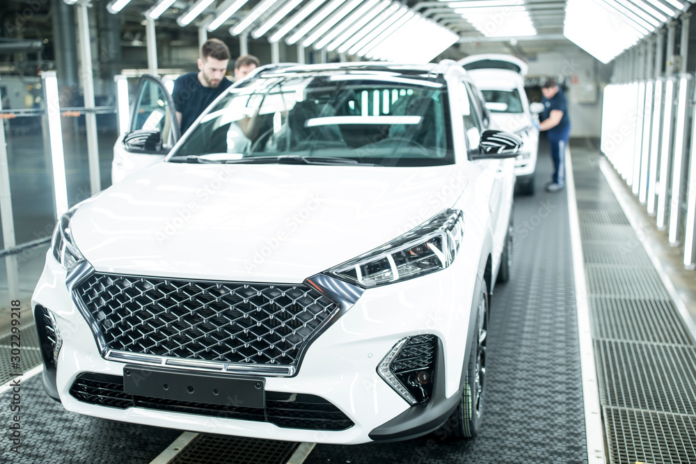 Colleagues working in modern car factory Colleagues working in modern car factory