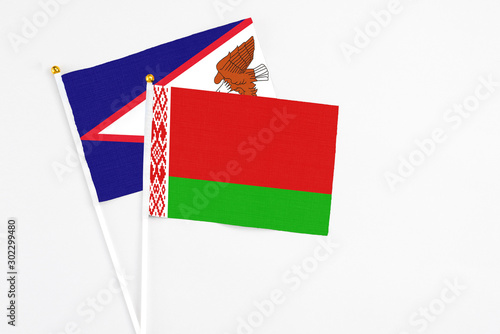 Belarus and American Samoa stick flags on white background. High quality fabric, miniature national flag. Peaceful global concept.White floor for copy space. photo