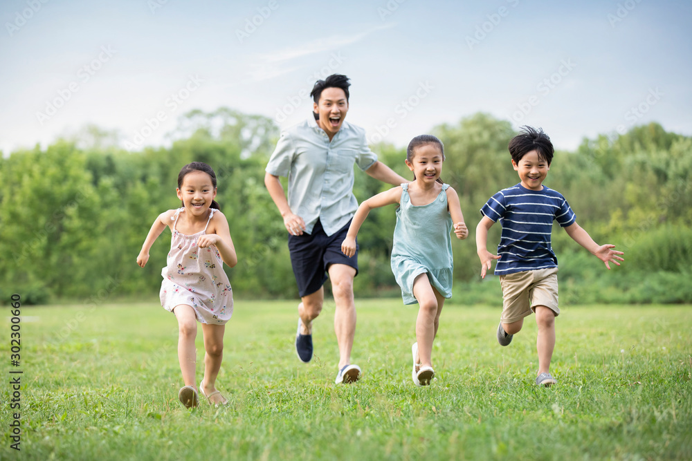 Happy young Chinese family running on grass Happy young Chinese family running on grass