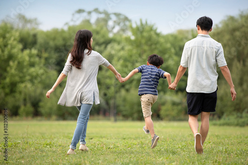 Happy young Chinese family walking on grass photo