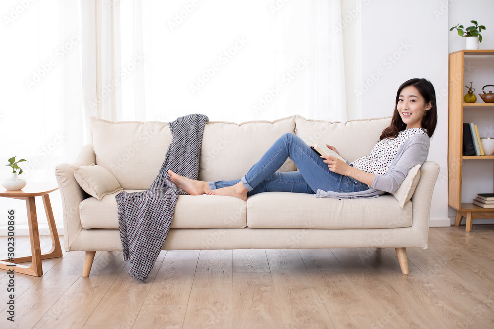 Happy young Chinese woman reading book on sofa Happy young Chinese woman reading book on sofa