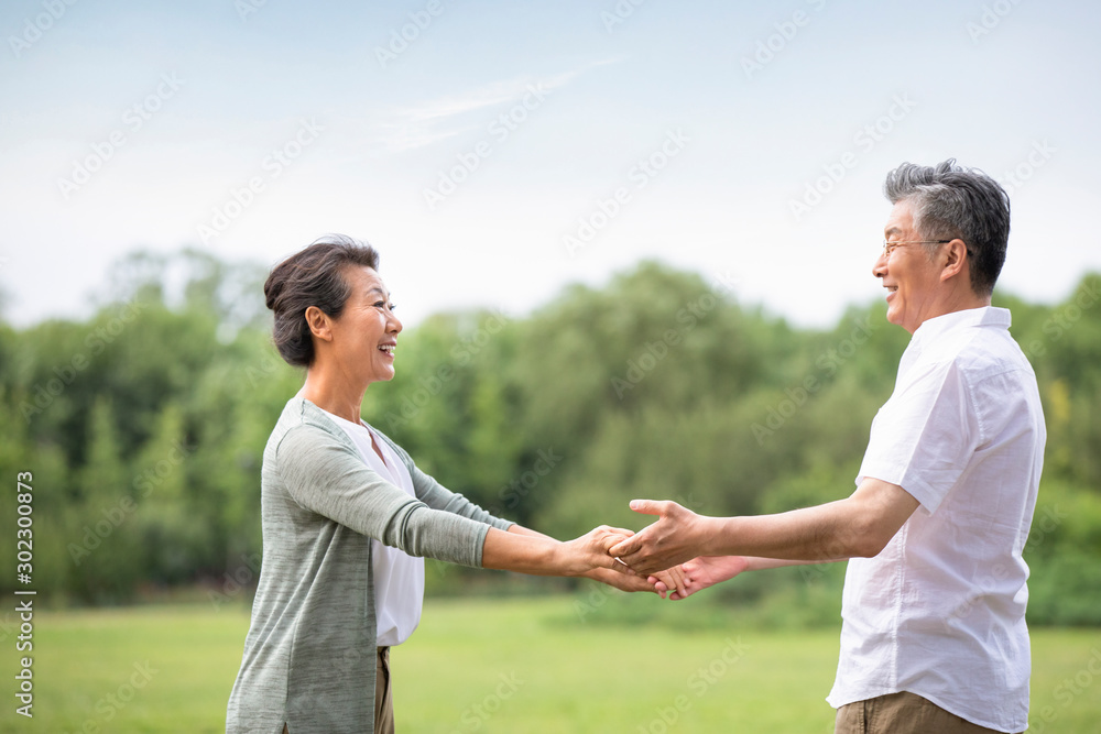 Happy senior Chinese couple dancing on grass Happy senior Chinese couple dancing on grass
