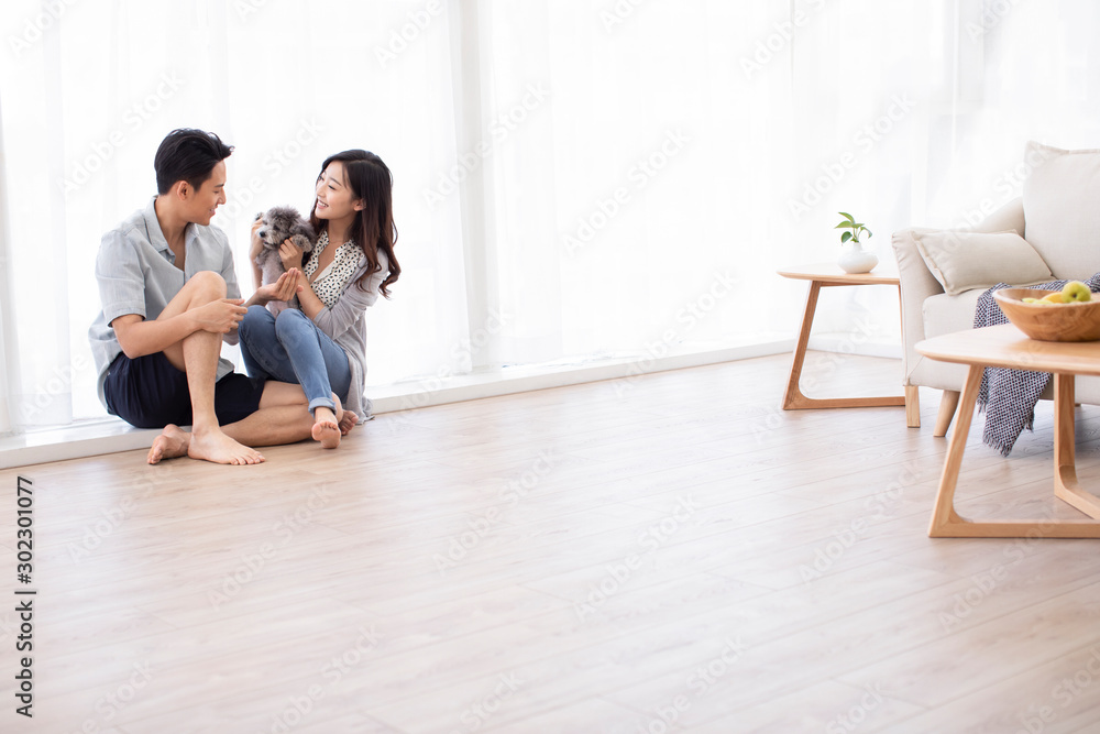Happy young Chinese couple playing with dog in living room Happy young Chinese couple playing with dog in living room