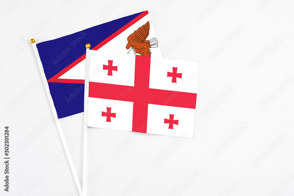 Georgia and American Samoa stick flags on white background. High quality fabric, miniature national flag. Peaceful global concept.White floor for copy space.