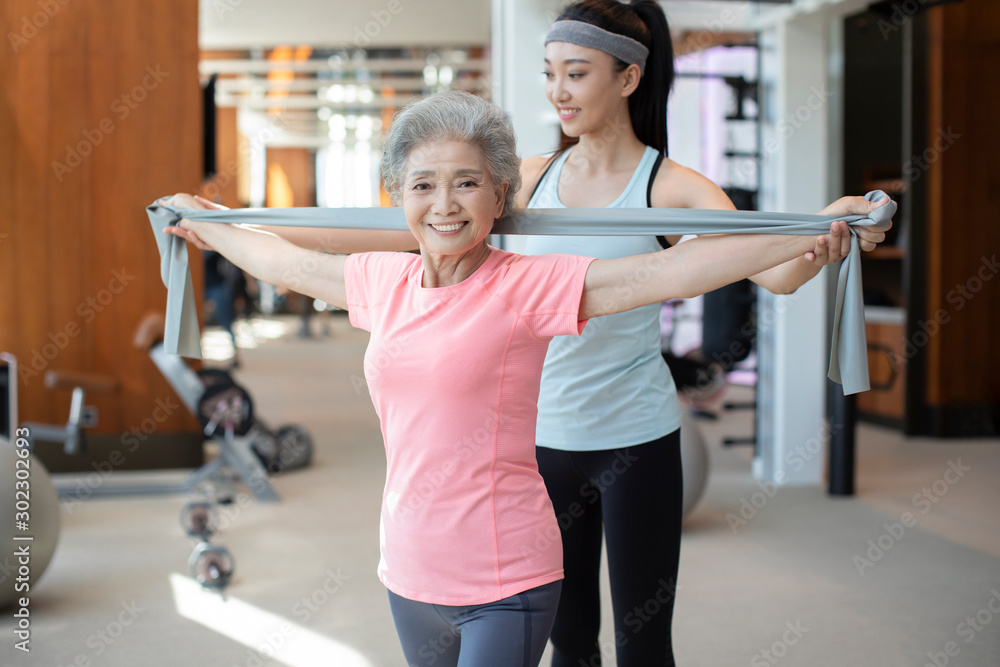 Senior Chinese woman working out with personal trainer at gym Senior Chinese woman working out with personal trainer at gym