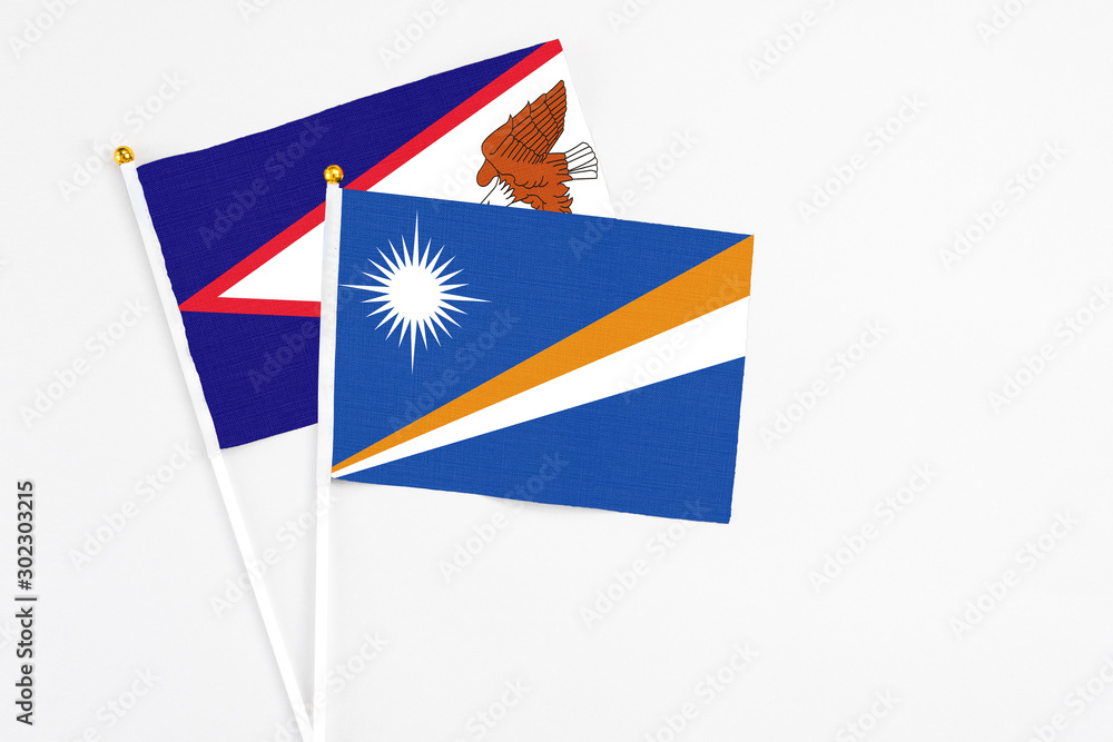 Marshall Islands and American Samoa stick flags on white background. High quality fabric, miniature national flag. Peaceful global concept.White floor for copy space. Marshall Islands and American Samoa stick flags on white background. High quality fabric, miniature national flag. Peaceful global concept.White floor for copy space.