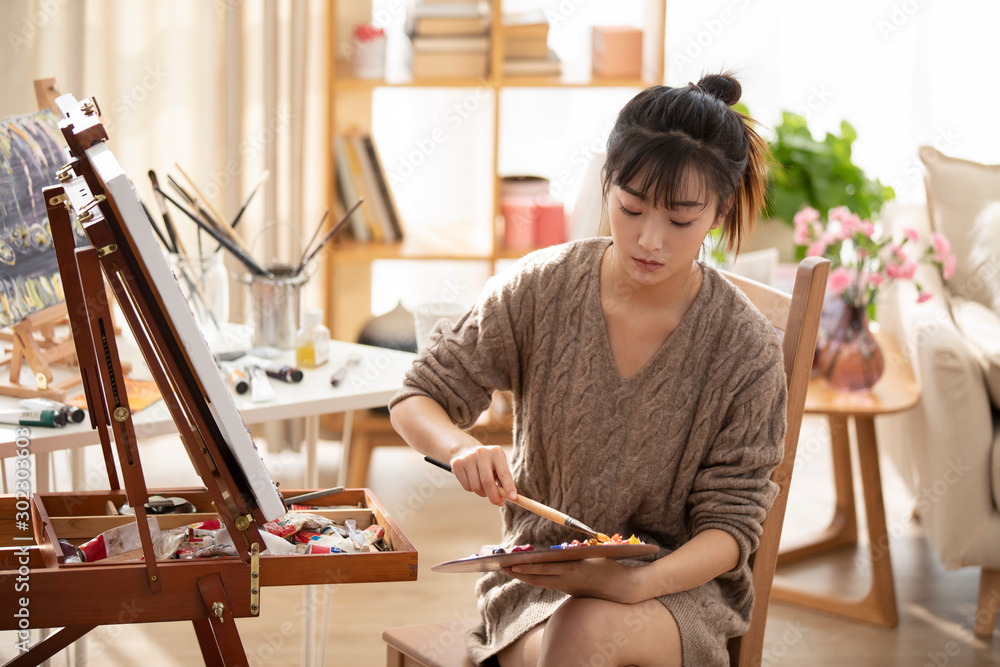 Young Chinese woman painting at home Young Chinese woman painting at home