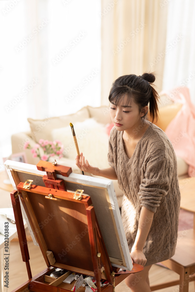 Young Chinese woman painting at home Young Chinese woman painting at home