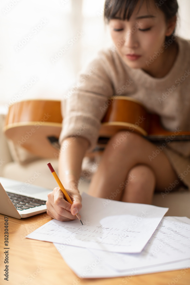 Young Chinese woman writing music at home Young Chinese woman writing music at home