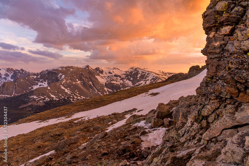 Sunset Spring Mountains - Colorful sunset clouds hanging over Forest Canyon and snow-capped peaks of Continental Divide, as seen from top of Tundra Communities Trail, Rocky Mountain National Park, CO.