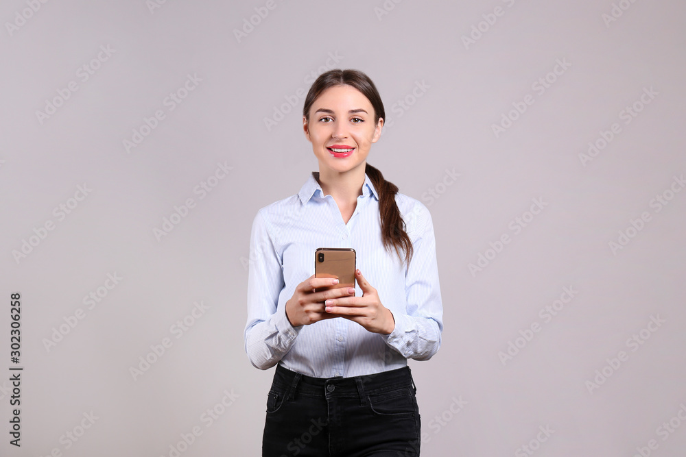 Cheerful attractive young businesswoman in glasses standing and using mobile phone over white background Cheerful attractive young businesswoman in glasses standing and using mobile phone over white background