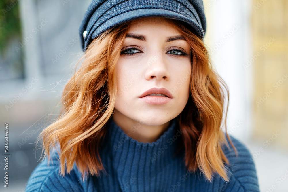 Portrait of a beautiful red-haired girl in a blue sweater and hat. Close up Portrait of a beautiful red-haired girl in a blue sweater and hat. Close up