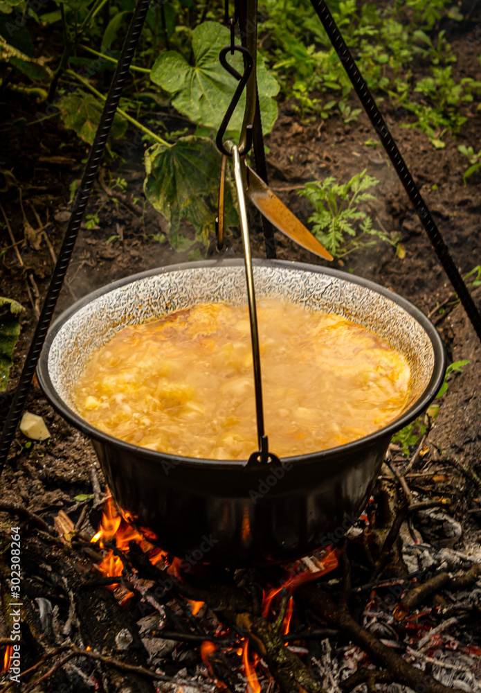 Cooking traditional Hungarian goulash soup in a cauldron outdoors