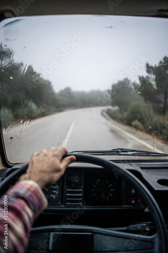 Driver riding car along rural pathway at forest in rain photo