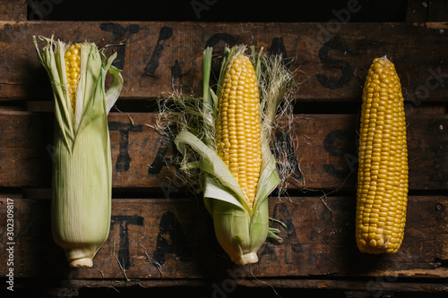 Top view of steps of fresh ripe corn peeling on wooden table