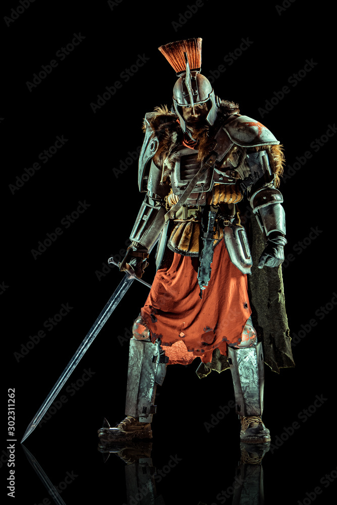 Powerful knight in the armor with the sword. Isolated on black background.