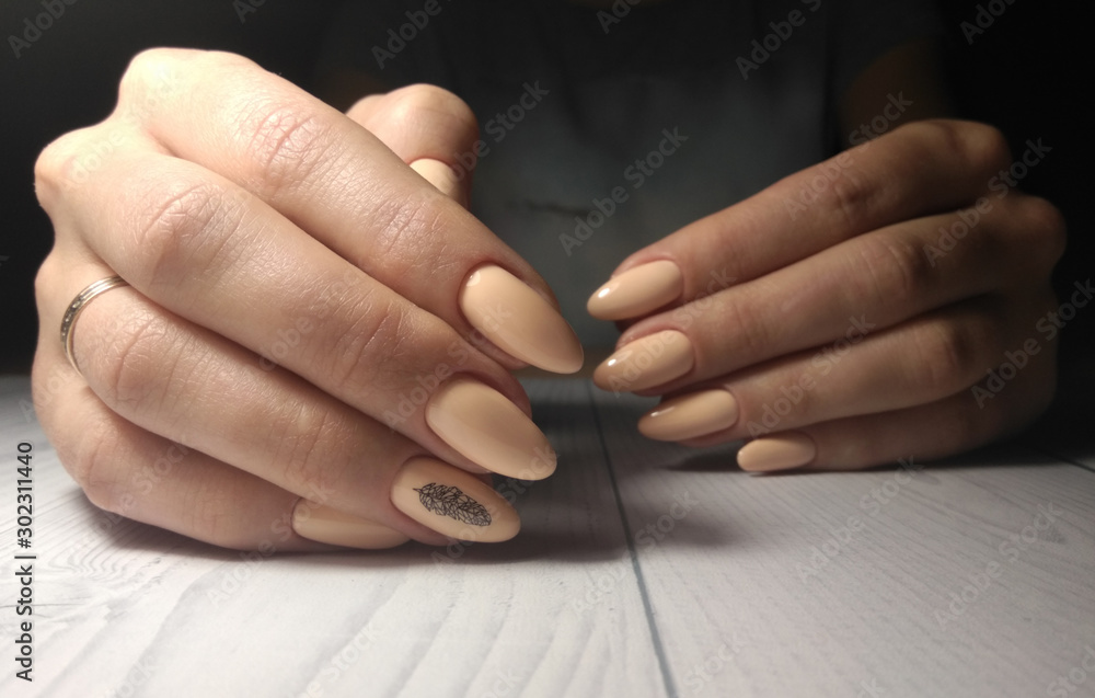 Obraz premium Peach gel polish with black geometric pen design. Black leaf design consisting of geometric details on camouflage pastel coating on long round nails.