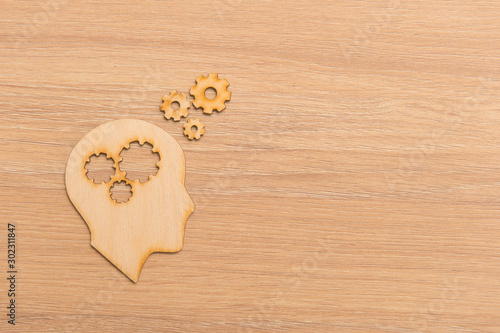 Business and design concept - wooden man head silhouette with gear icon on wooden background