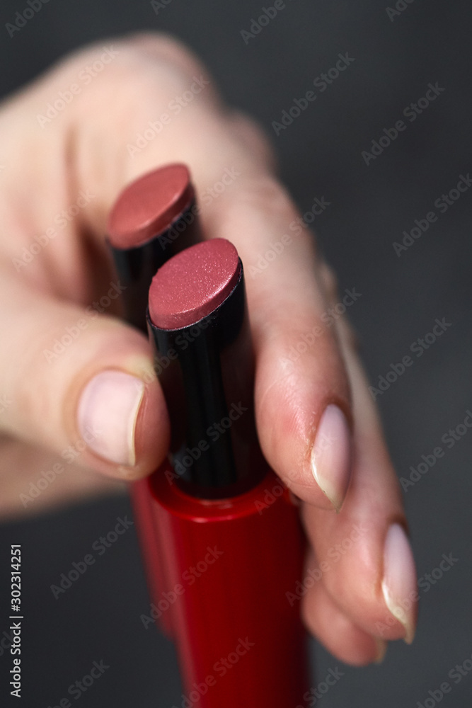 Woman's beauty blogger palm holding bottles and tubes spa professional hi-end cosmetics red lipsticks applies sample tone color on skin with copyspace Woman's beauty blogger palm holding bottles and tubes spa professional hi-end cosmetics red lipsticks applies sample tone color on skin with copyspace