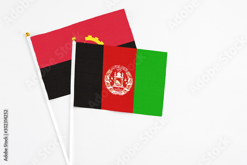Afghanistan and Angola stick flags on white background. High quality fabric, miniature national flag. Peaceful global concept.White floor for copy space.