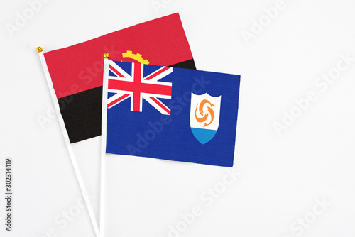 Anguilla and Angola stick flags on white background. High quality fabric, miniature national flag. Peaceful global concept.White floor for copy space.