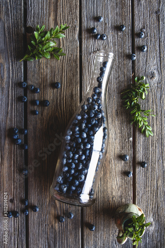 Blueberries in a bottle on wooden background