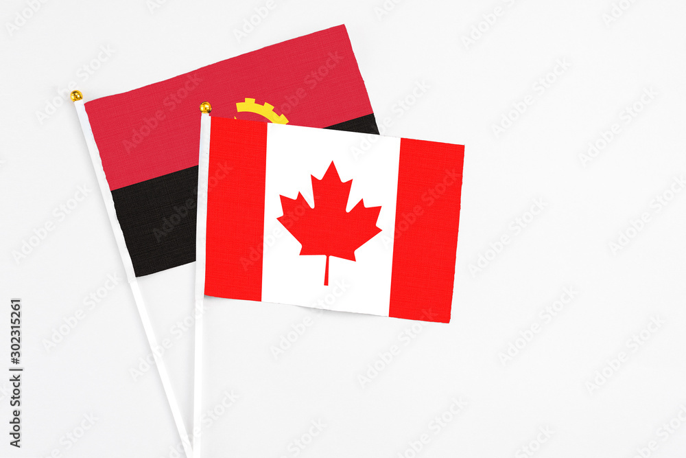 Canada and Angola stick flags on white background. High quality fabric, miniature national flag. Peaceful global concept.White floor for copy space. Canada and Angola stick flags on white background. High quality fabric, miniature national flag. Peaceful global concept.White floor for copy space.