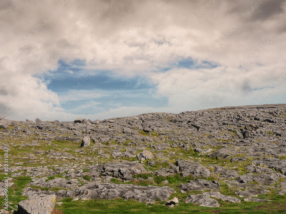 Rough stone terrain in the mountains, Burren National park, county Clare, Ireland. Blue cloudy sky in the background.