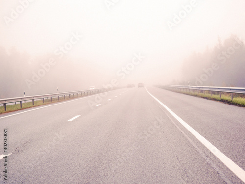 Cars on a road in a fog, concept danger, driving in low visibility condition.