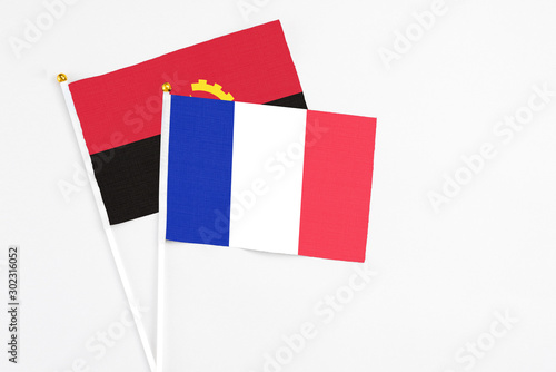 France and Angola stick flags on white background. High quality fabric, miniature national flag. Peaceful global concept.White floor for copy space. photo