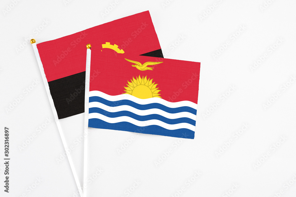 Naklejka premium Kiribati and Angola stick flags on white background. High quality fabric, miniature national flag. Peaceful global concept.White floor for copy space.