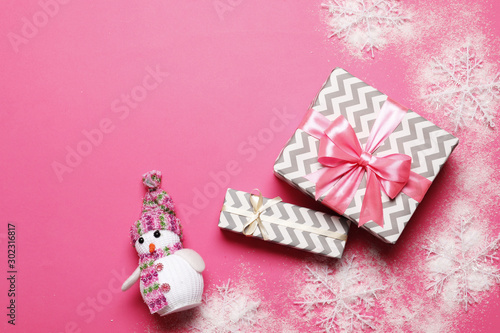 Gift boxes with a pink bow and a snowman on a pink background. place for text. Top view.