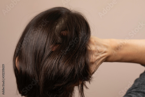 Back view of brunette woman scratching head