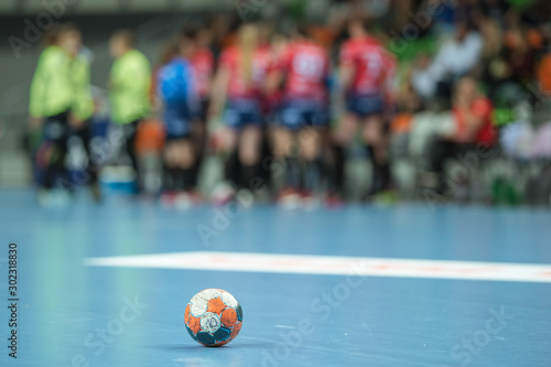 Handball ball lying on the blue parquet .
